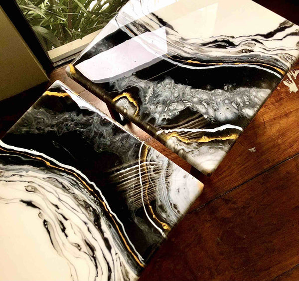 Two artistic tables coated with Onyx SURFACE Z90 Epoxy Resin with marble like design effects of waving black white and gold pigment highlights using Mica Peal Luster Metallic Powder Pigments 